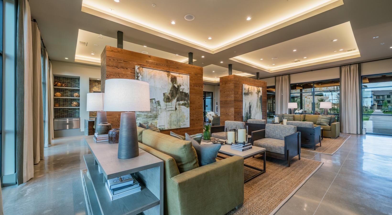 Modern hotel lobby with gray sofas, teal chairs, stone walls, and warm recessed lighting