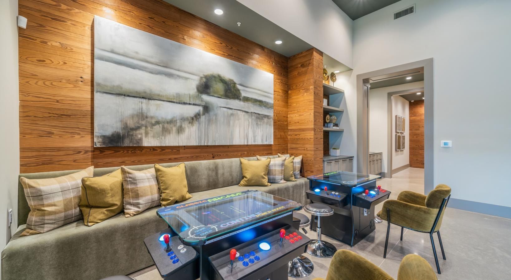 Modern lobby with tan sofa, glass coffee table, abstract wall art, and blue accent chairs