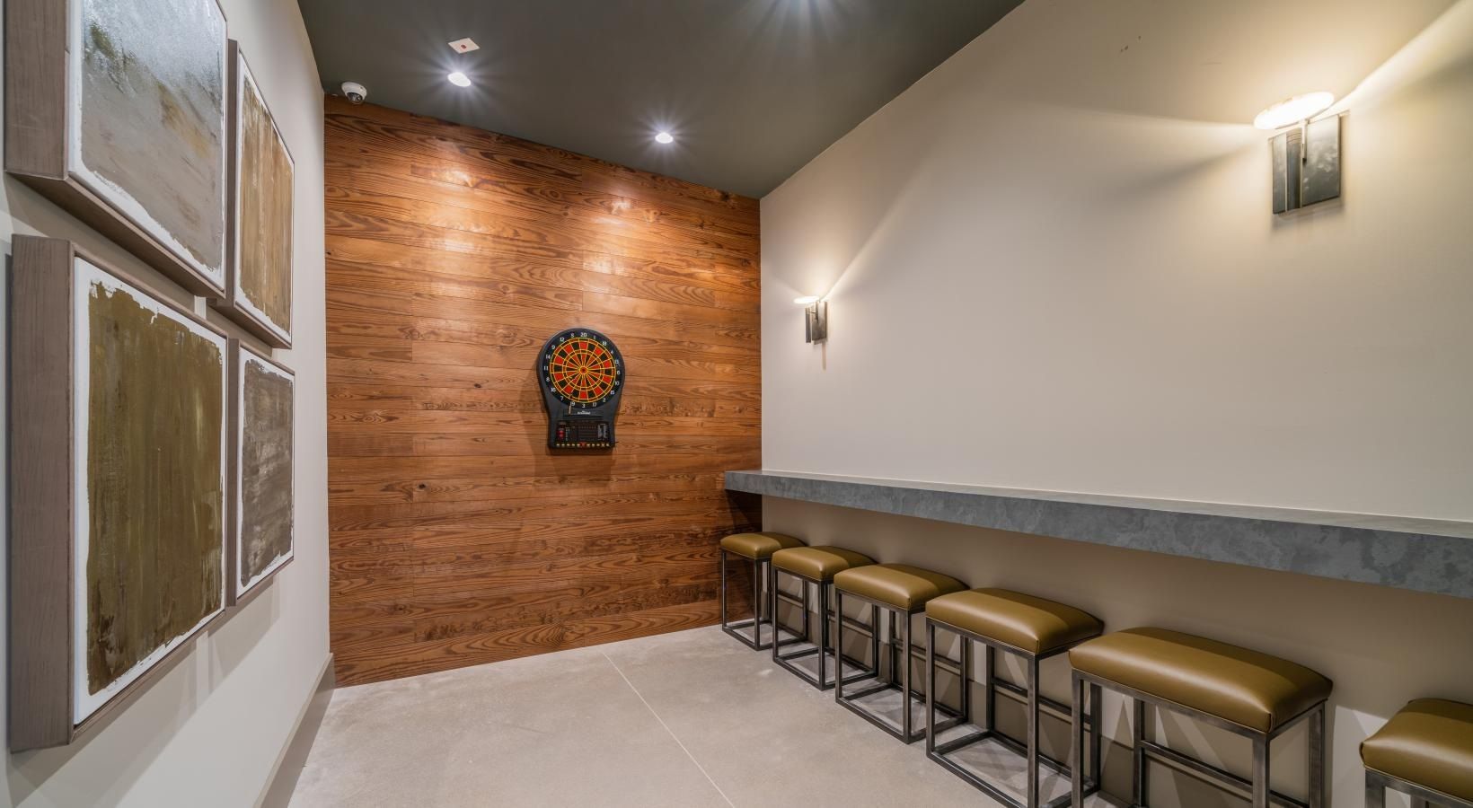 Modern hallway with wood accent wall, long ledge, and row of stools beneath wall lights.