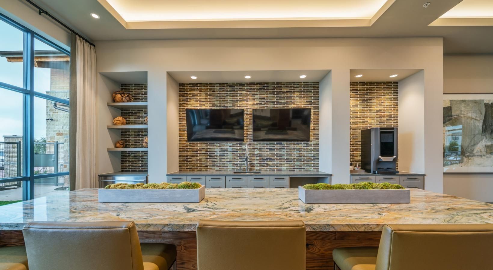 Modern conference room with a long table, tan chairs, and a wall-mounted TV above a stone fireplace.