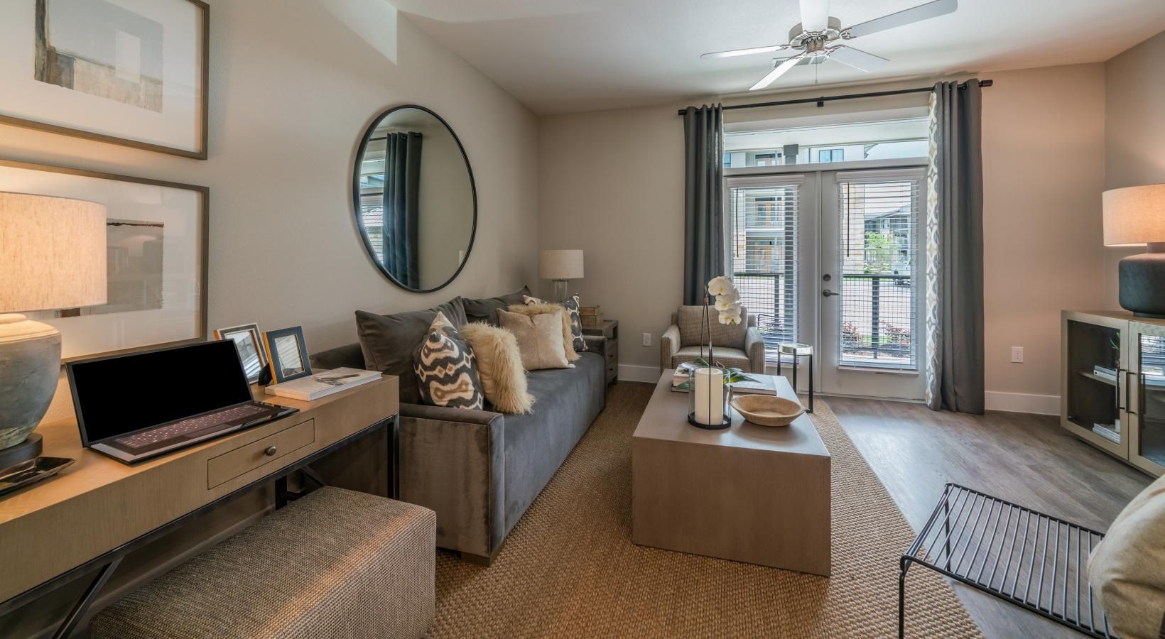 Bright modern living room with sofa, desk, TV, and balcony doors, in neutral beige tones