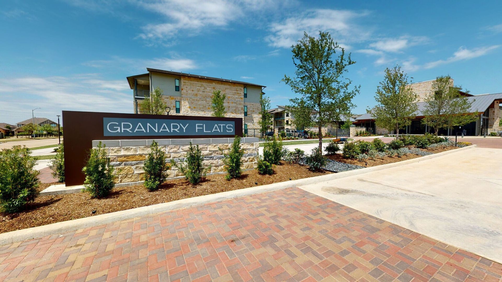 Grandview Flats entrance sign beside a landscaped sidewalk under a blue sky