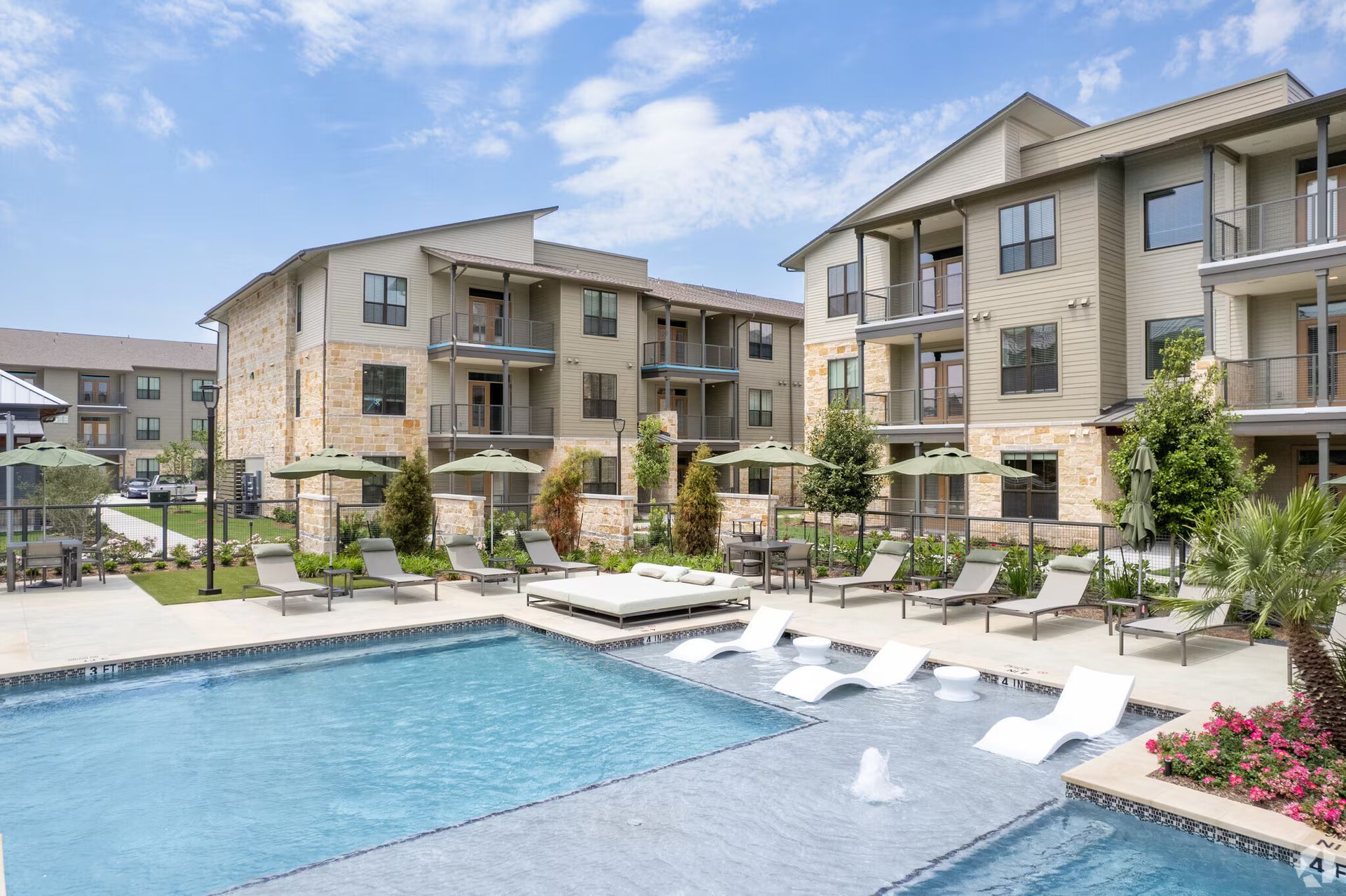 Apartment complex courtyard with a swimming pool, lounge chairs, and landscaped seating areas
