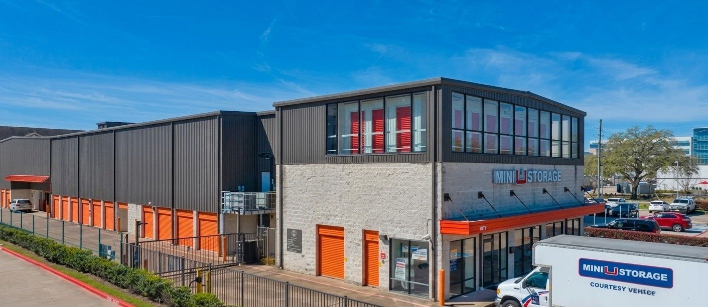 Modern commercial building with black and gray exterior and orange accents under a blue sky