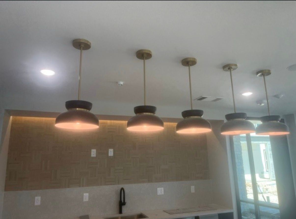 Modern kitchen with three pendant lights over a counter and tan backsplash