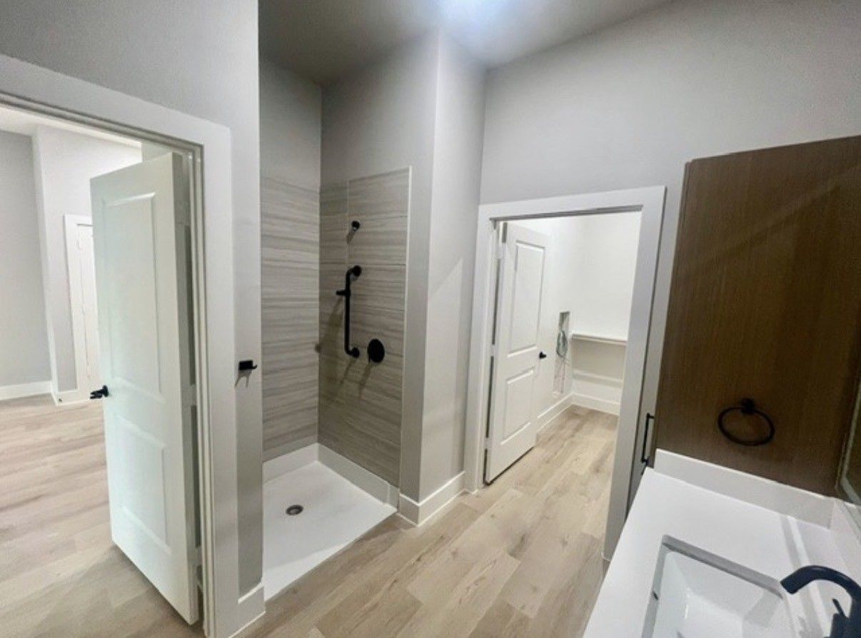 Bright modern bathroom with shower, toilet, sink, and wood-look flooring