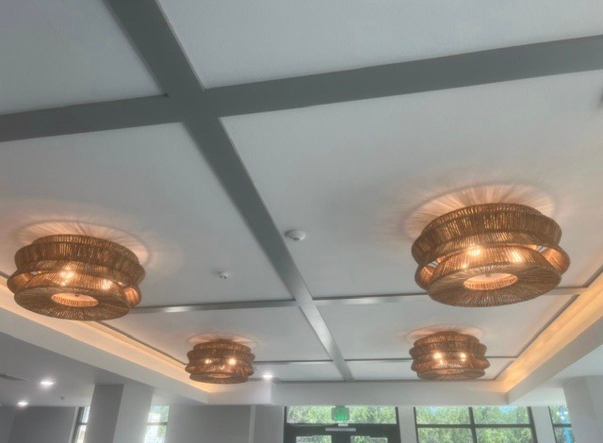 Ceiling with four ornate bronze chandeliers in a bright modern room