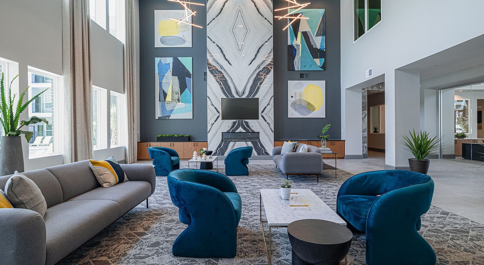 Modern living room with gray sofa, blue chairs, coffee table, and large abstract wall art