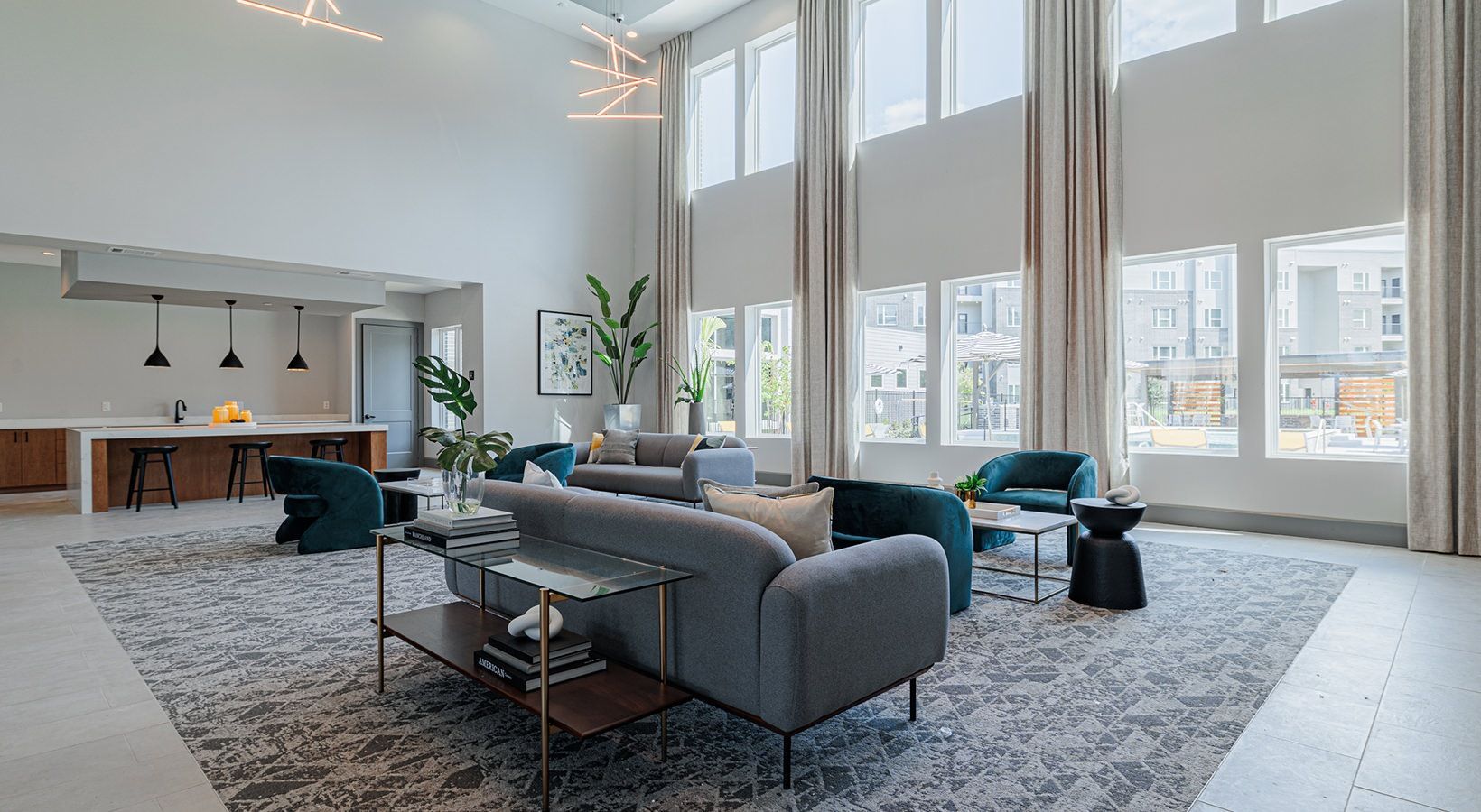 Modern open living room with gray sofas, large windows, rug, and fireplace in a bright loft apartment