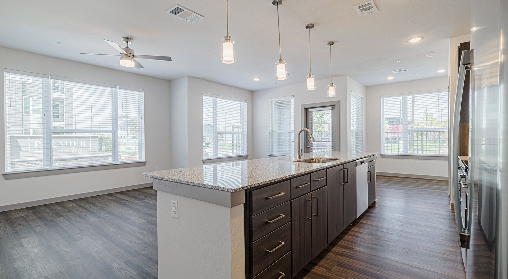 Spacious modern kitchen and dining area with island, white walls, gray floors, and large windows