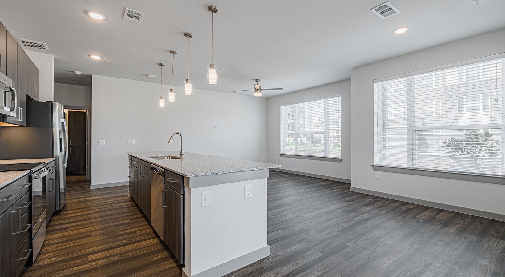 Modern open-concept kitchen and living area with dark floors, white walls, large windows, and island seating