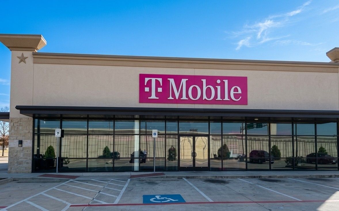 T-Mobile storefront with pink sign on a sunny strip mall exterior
