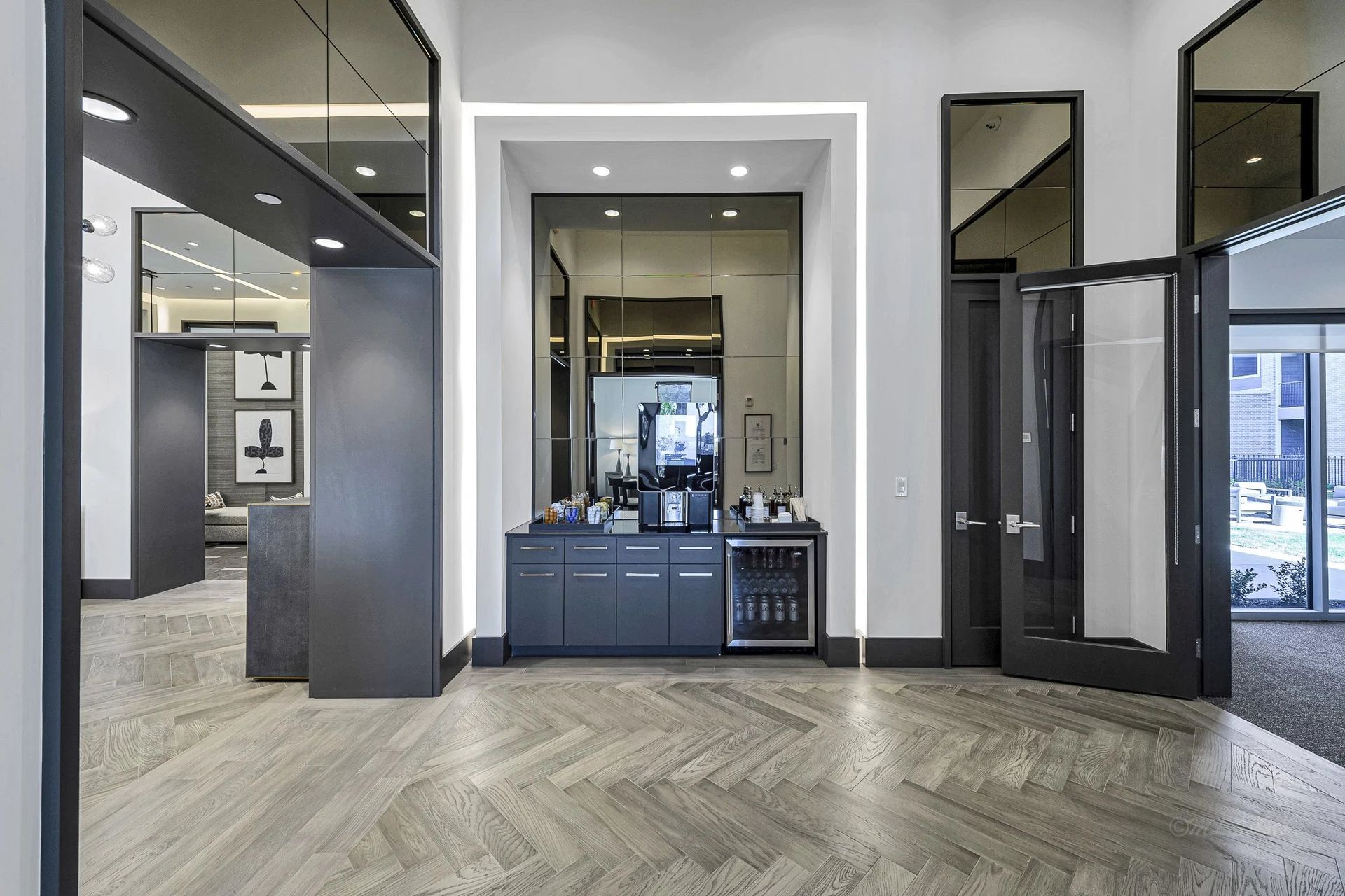 Modern office lobby with glass doors, gray walls, and a blue reception desk