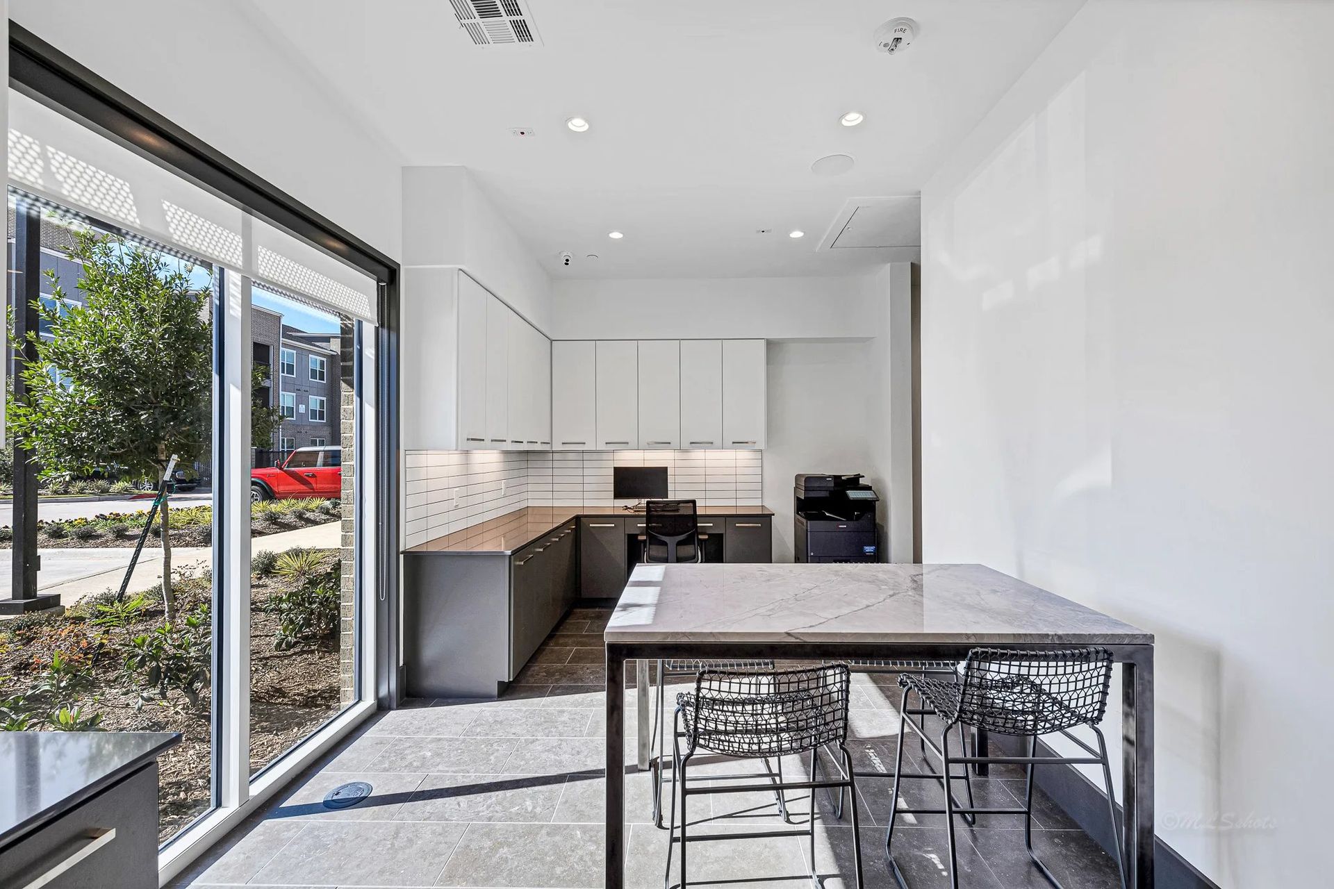 Bright modern kitchen with white cabinets, black countertops, and large sliding glass doors.