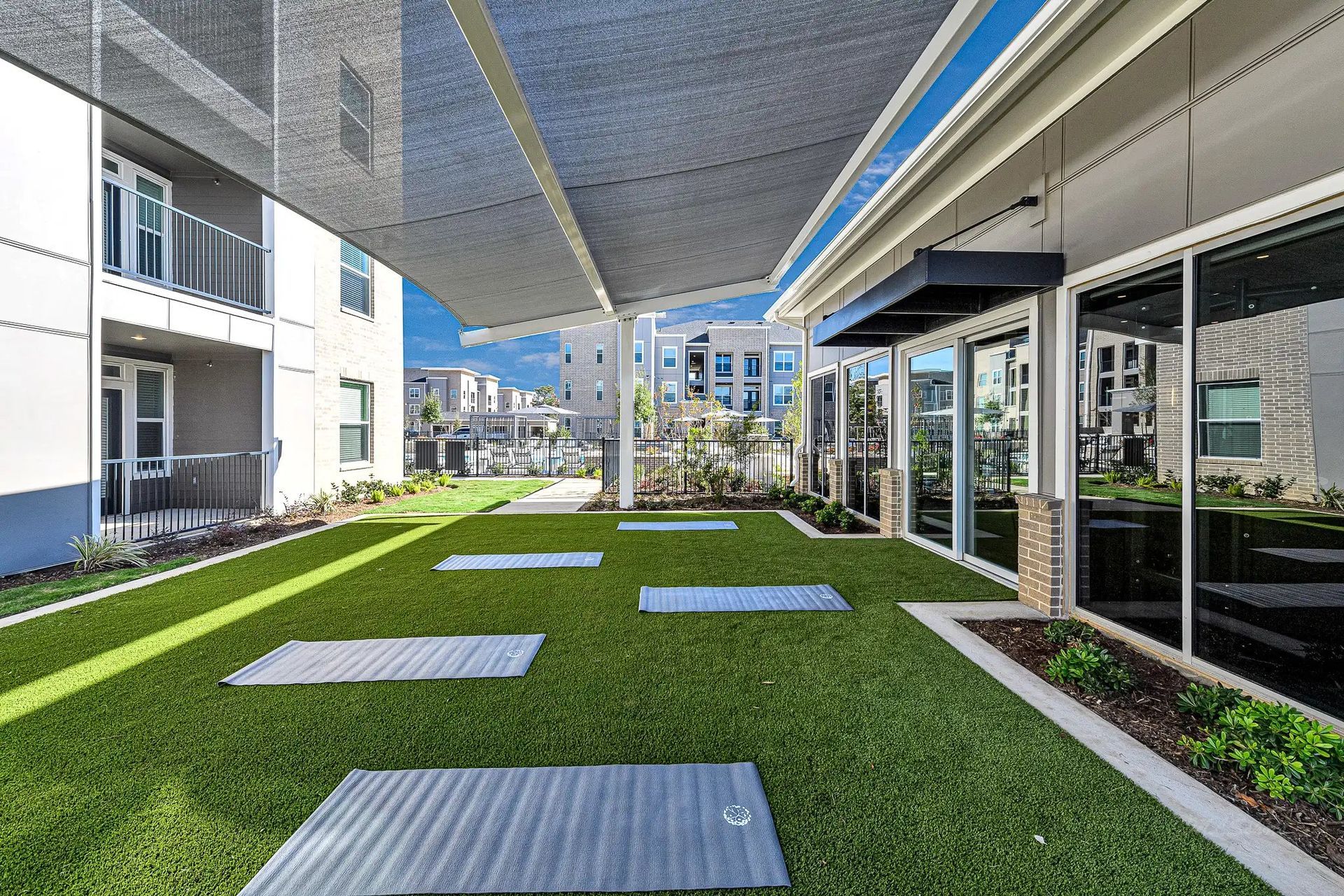 Modern apartment courtyard with artificial turf, concrete stepping stones, and covered walkways