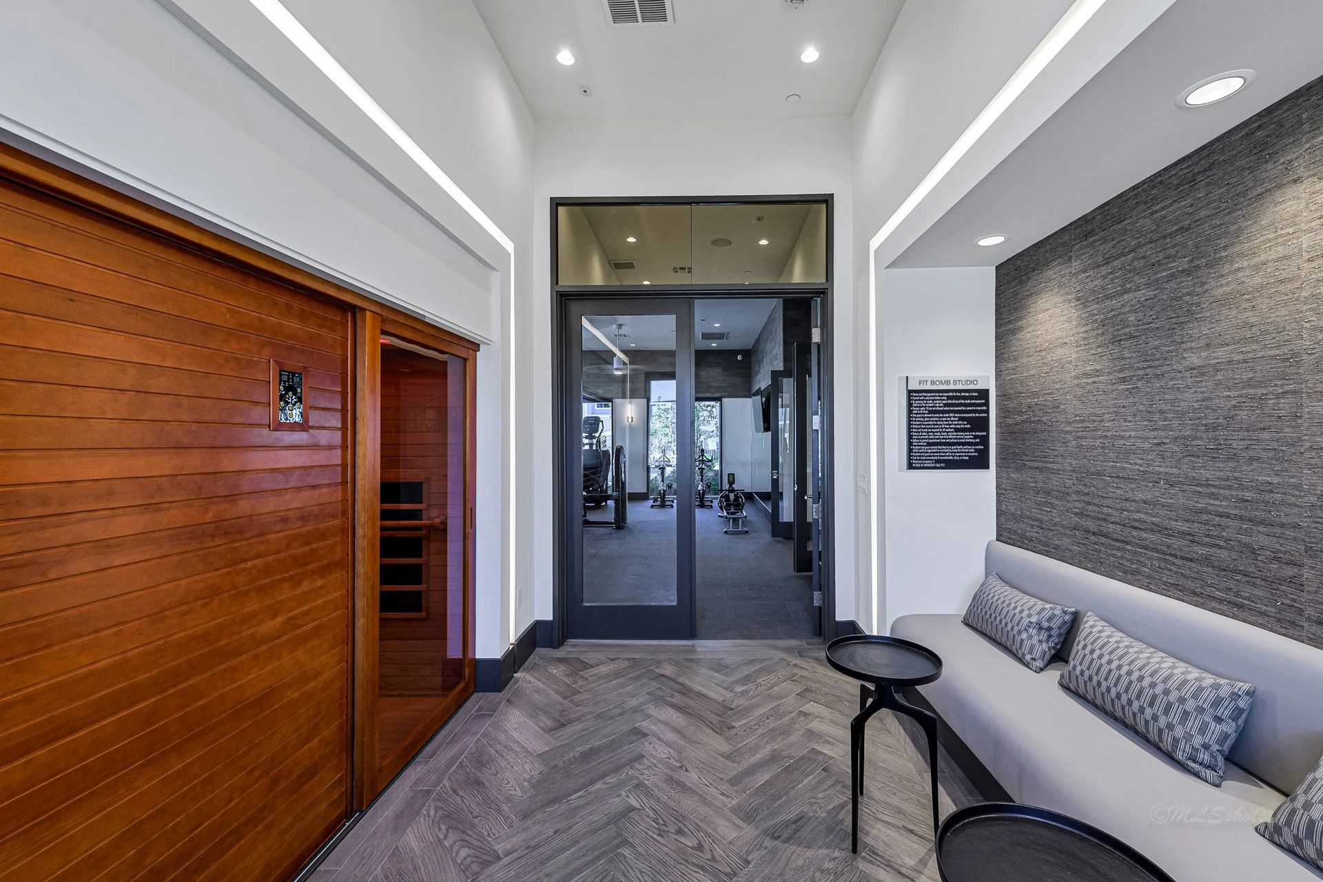 Modern office lobby with wood-paneled wall, gray seating, and glass entry doors