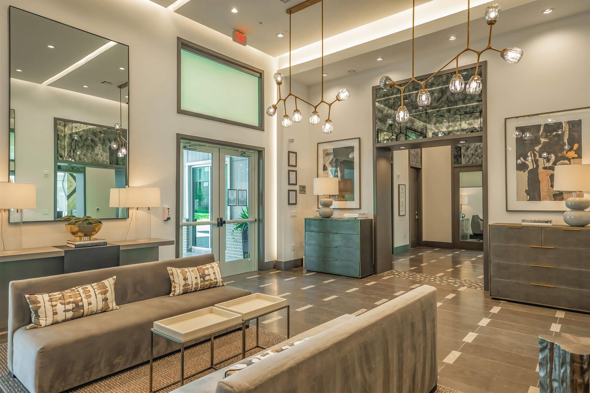 Modern spa lounge with mirrors, teal accents, seating, and glass doors in a bright interior