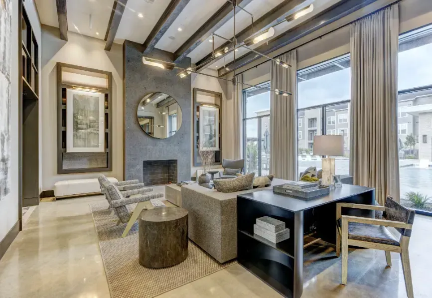 Modern living room with vaulted ceiling, gray sofas, large mirror, fireplace, and bright windows