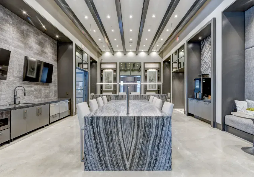 Modern luxury dining room with a marble table, recessed ceiling lights, and gray upholstered seating.