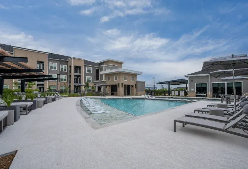 Apartment pool courtyard with lounge chairs, cabanas, and cloudy sky