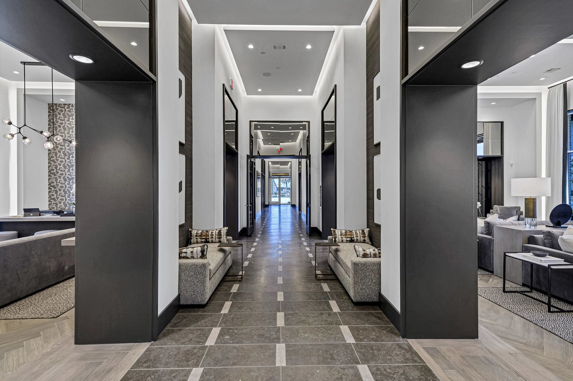 Modern hotel lobby with a central hallway, gray columns, and seating areas on both sides
