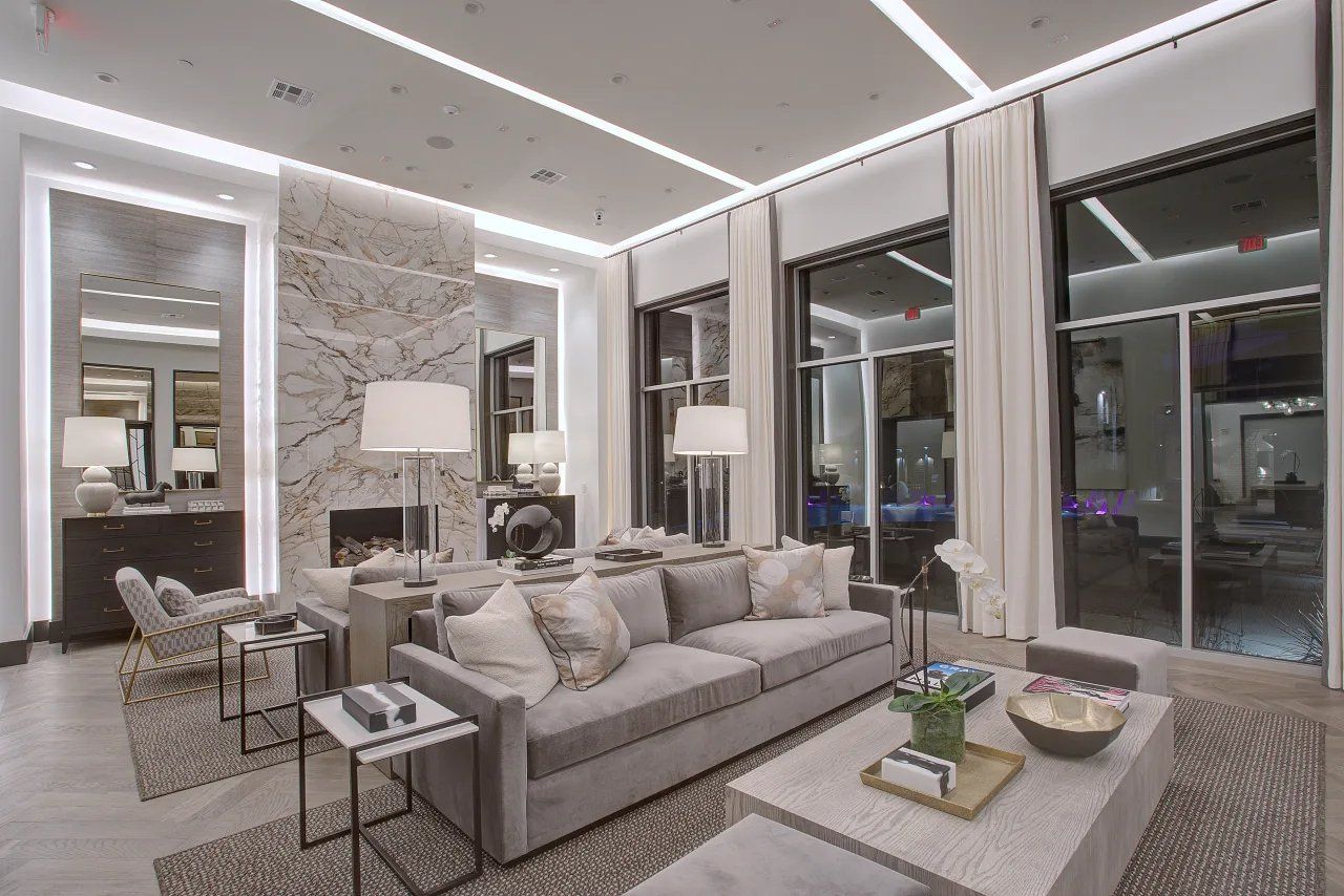 Modern living room with gray sofas, patterned chairs, and floor-to-ceiling windows at night