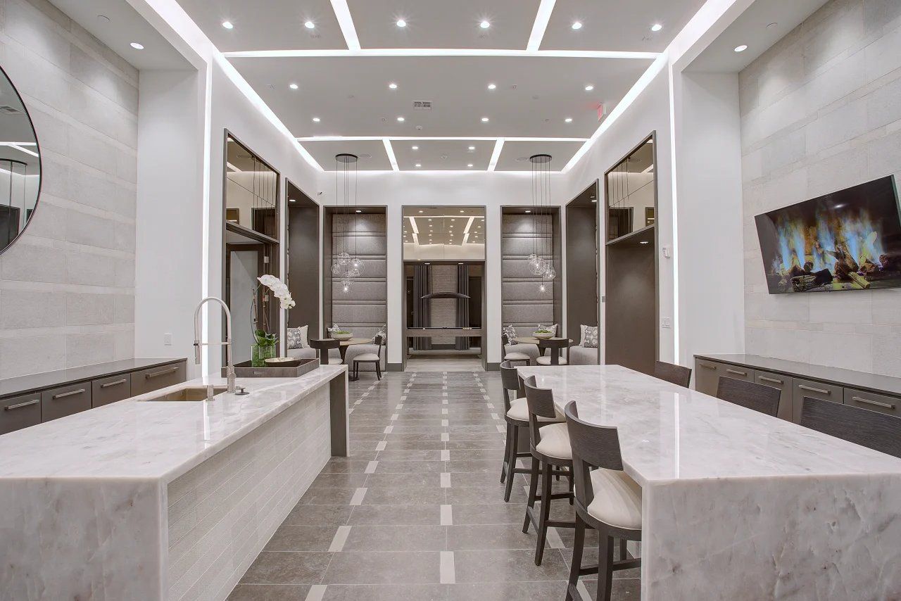 Modern kitchen with large marble island, bar stools, and recessed ceiling lights