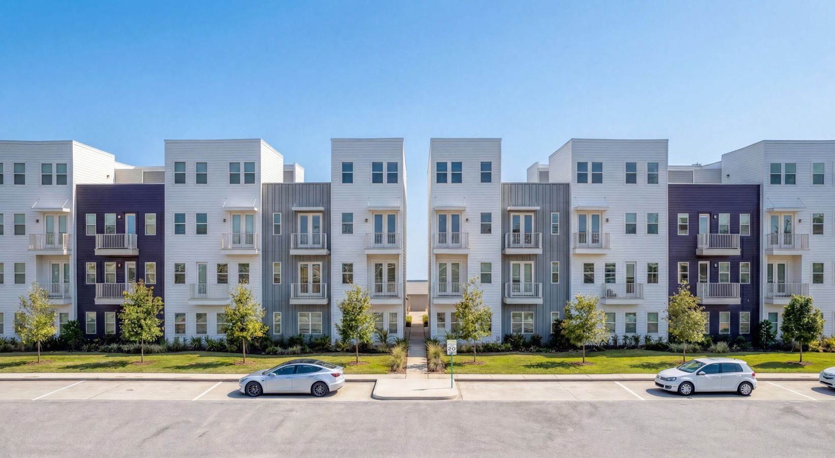 Row of modern apartment buildings with parked cars in front on a sunny day