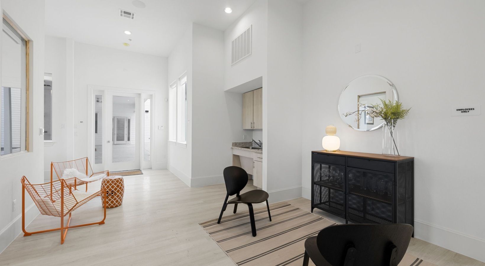 Bright white hallway with wicker chairs, a black console table, and a minimalist modern interior.