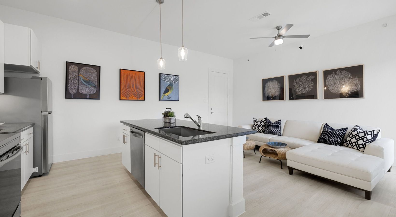 Bright open kitchen and living room with white walls, gray island, and white sectional sofa