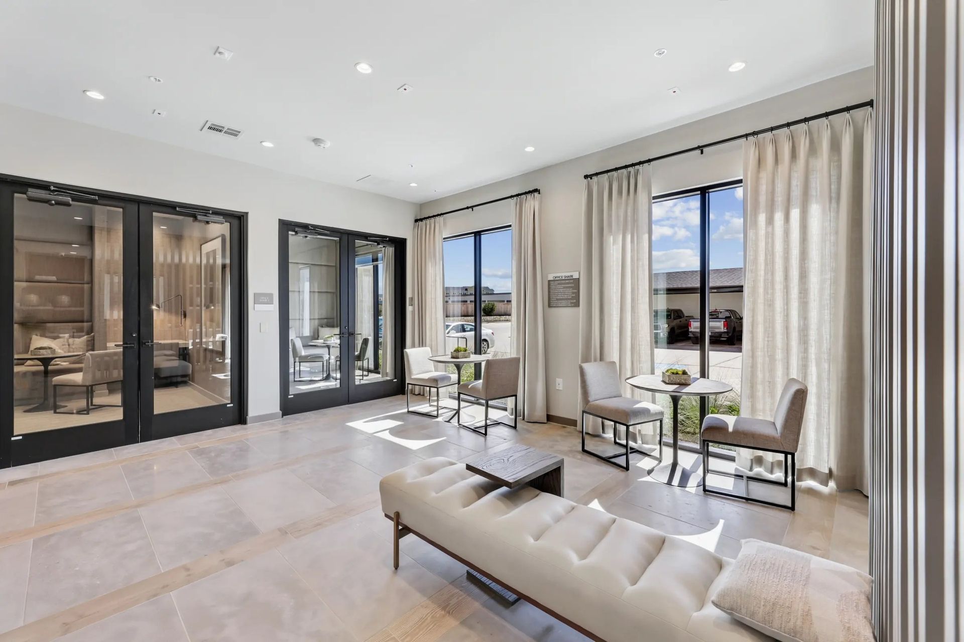 Bright modern living room with beige sofa, marble floor, tall curtains, and large glass doors to a patio