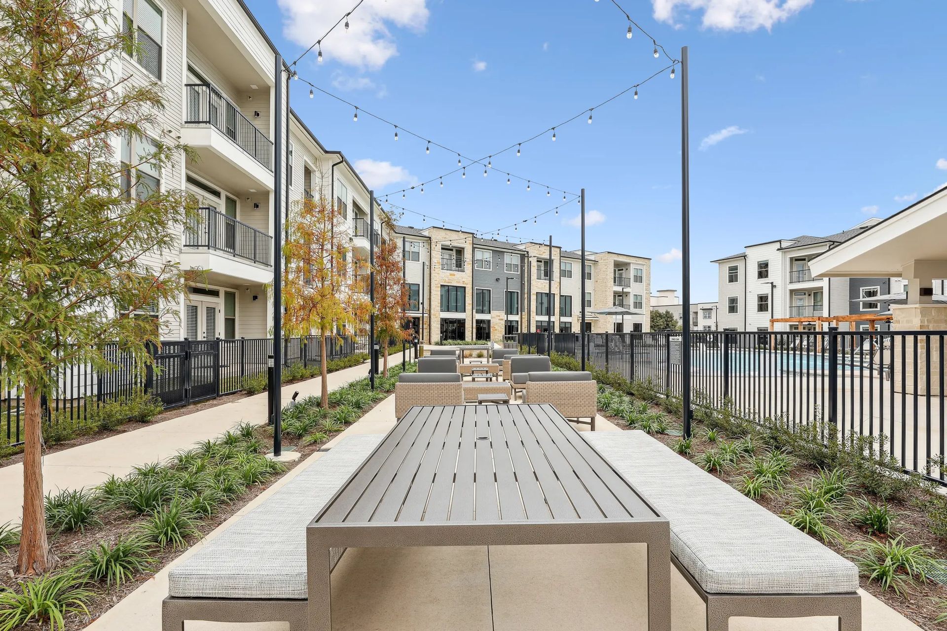 Outdoor courtyard with benches, raised planters, and apartment buildings under a blue sky