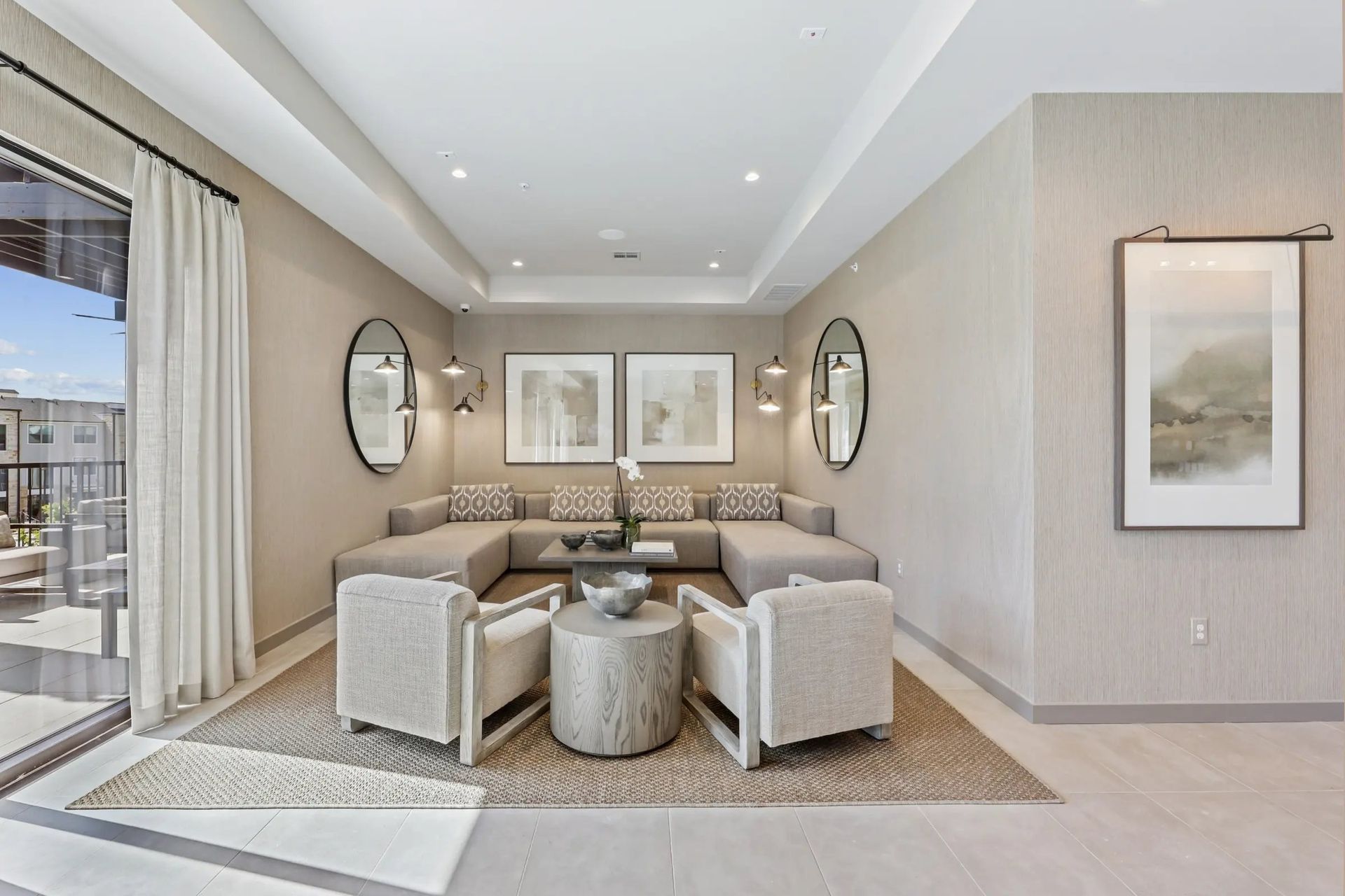 Modern beige living room with sectional sofa, round chairs, mirrored wall decor, and sliding glass doors