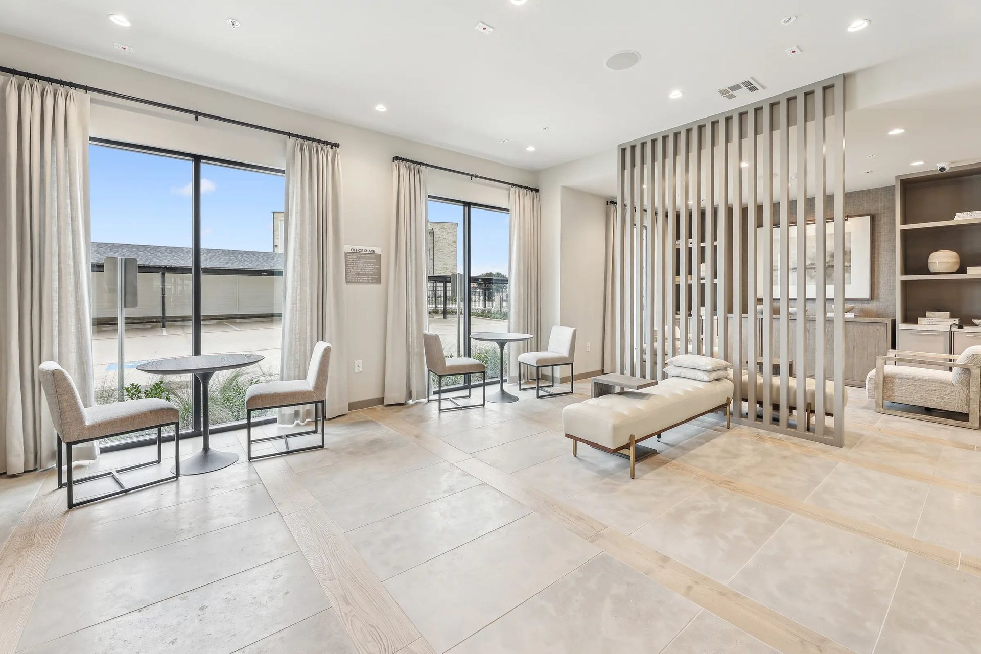 Bright modern living room with floor-to-ceiling windows, cream furniture, and a slatted room divider