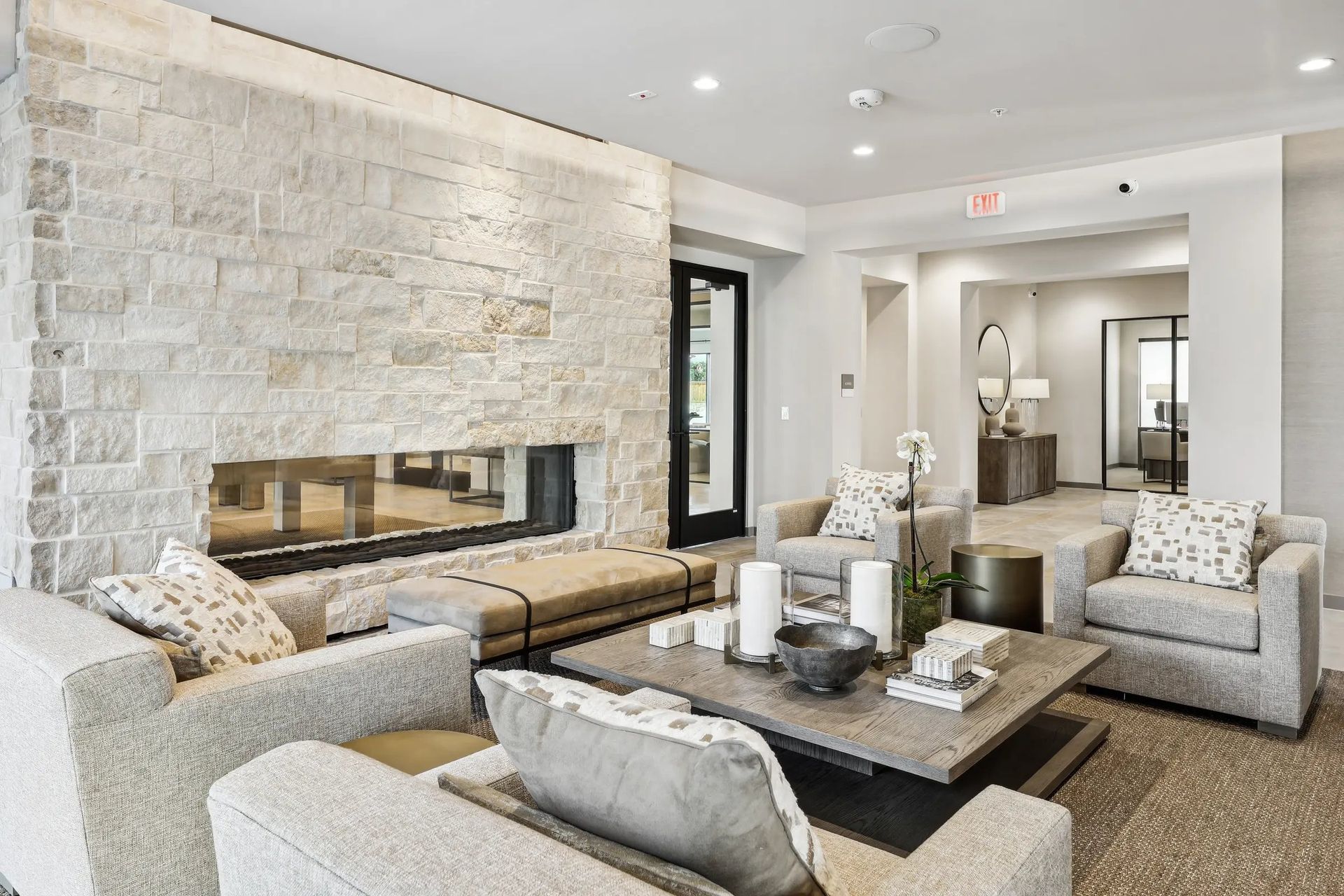 Bright modern lounge with stone fireplace, neutral sofas, and a central coffee table