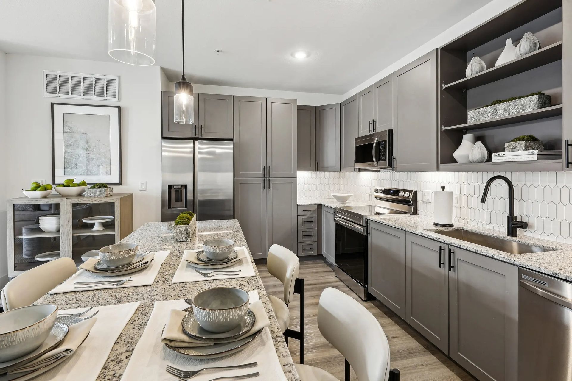 Modern gray-and-white kitchen with a set dining table and stainless steel appliances