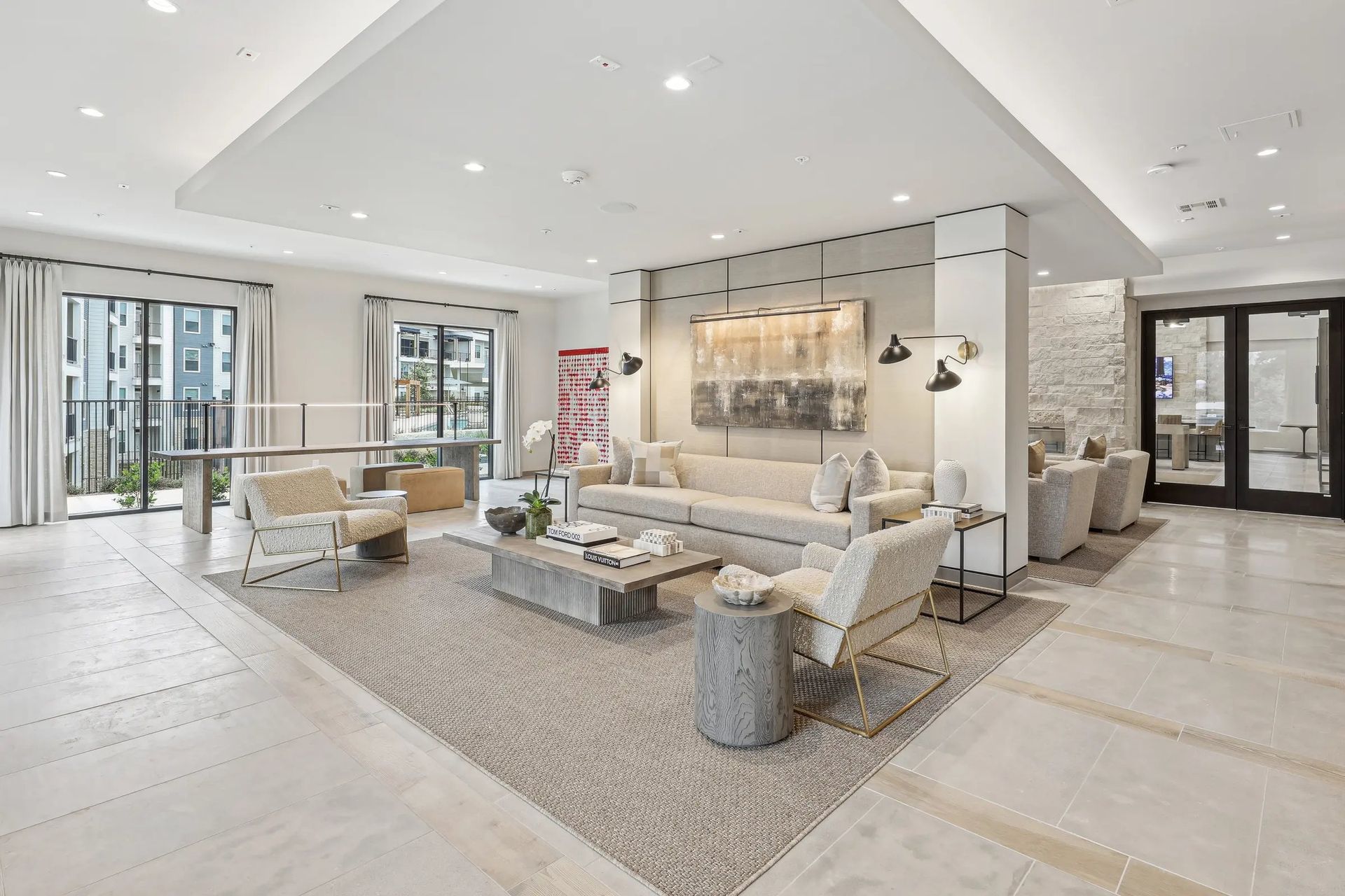 Bright modern lobby with cream sofas, rugs, artwork, and large windows in a spacious open room