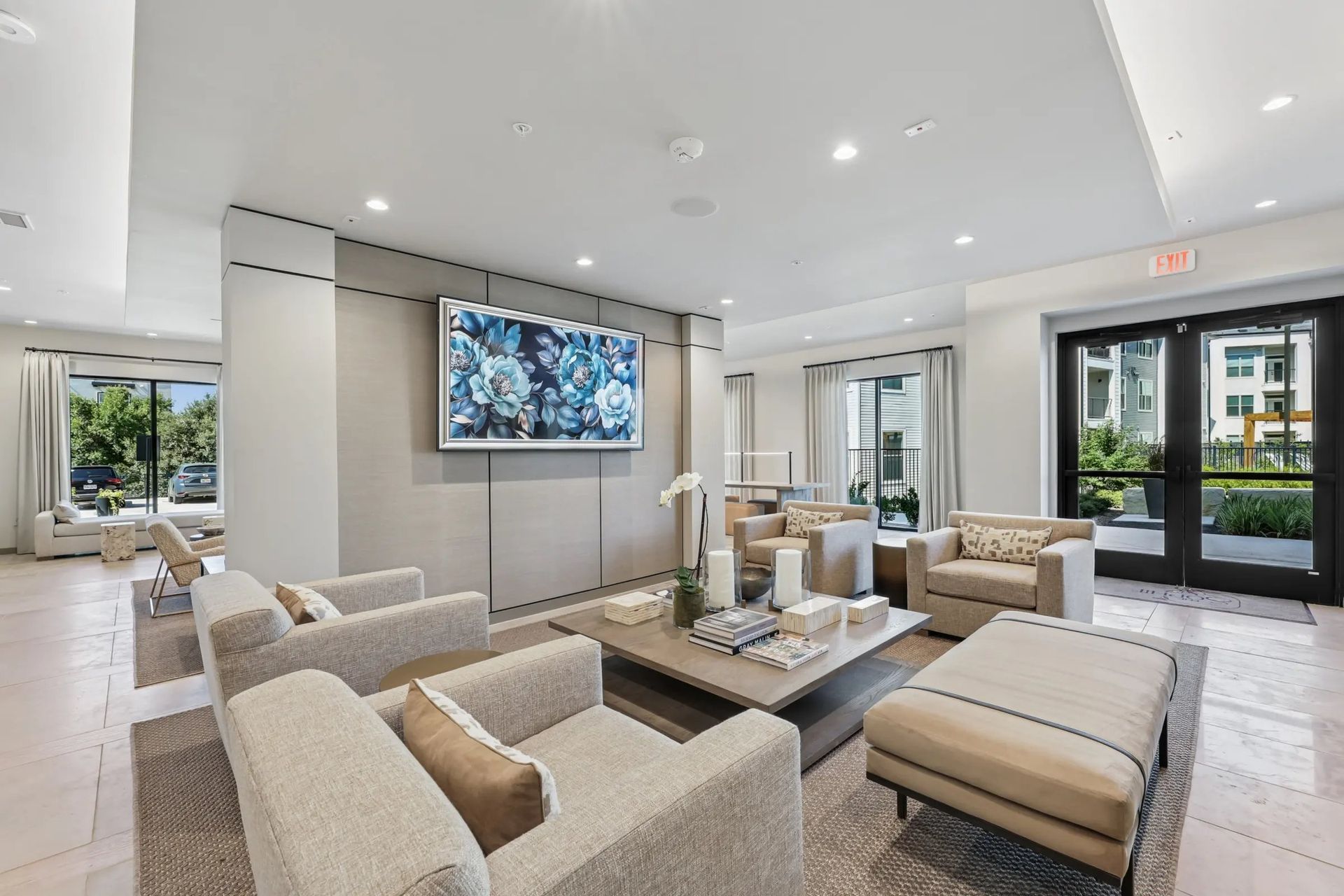 Modern luxury living room with beige sofas, wall-mounted TV, and large windows overlooking a balcony