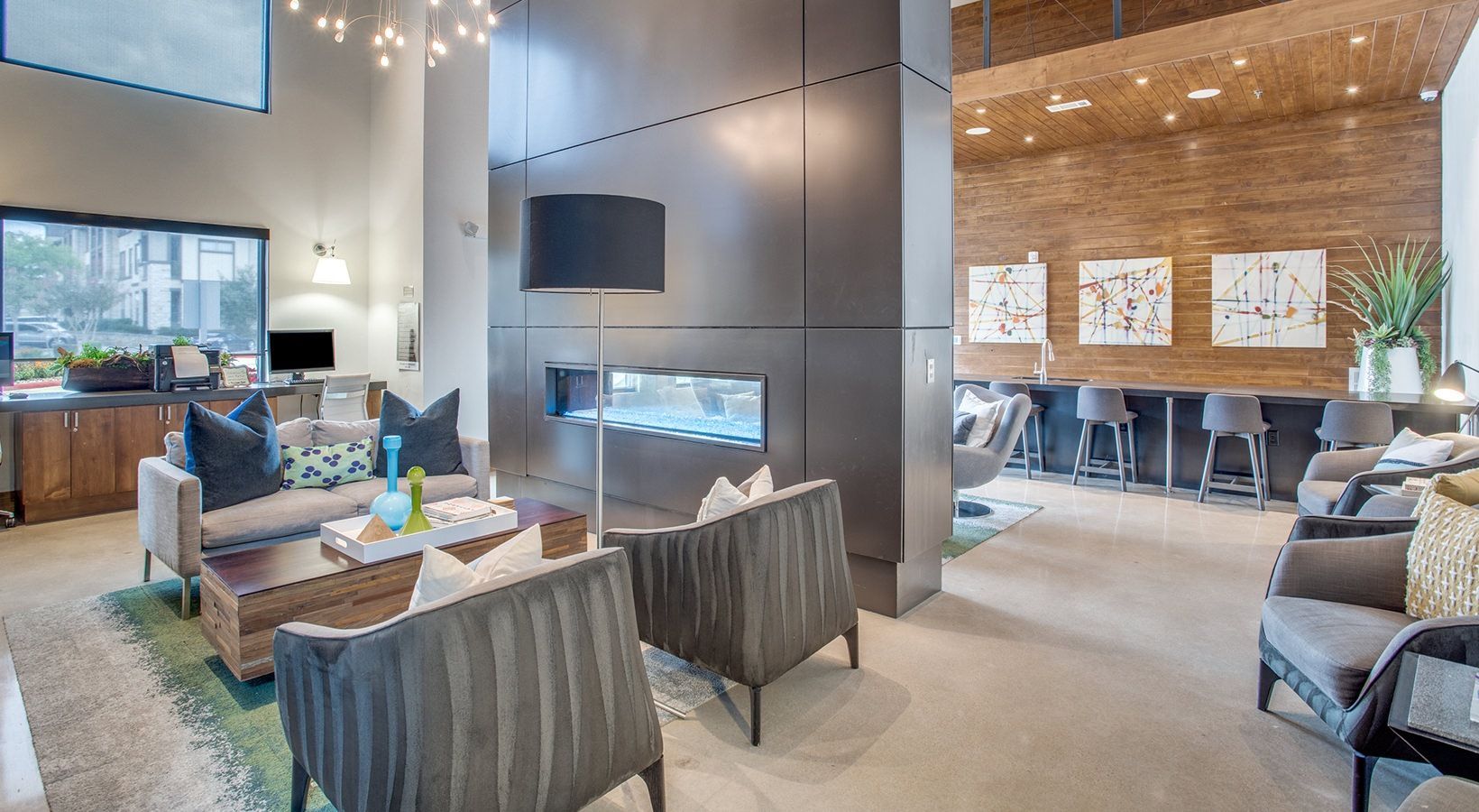 Modern living room with fireplace, gray chairs, a sofa, and an open dining area with wood accent wall