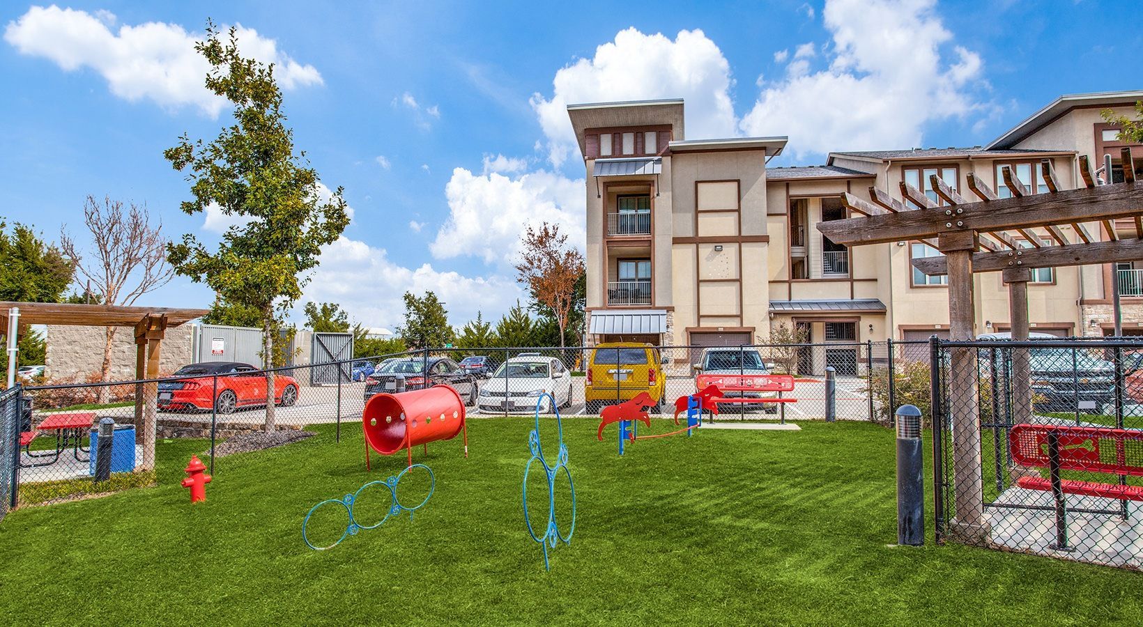 Outdoor playground with colorful play structures and a grassy area beside an apartment building