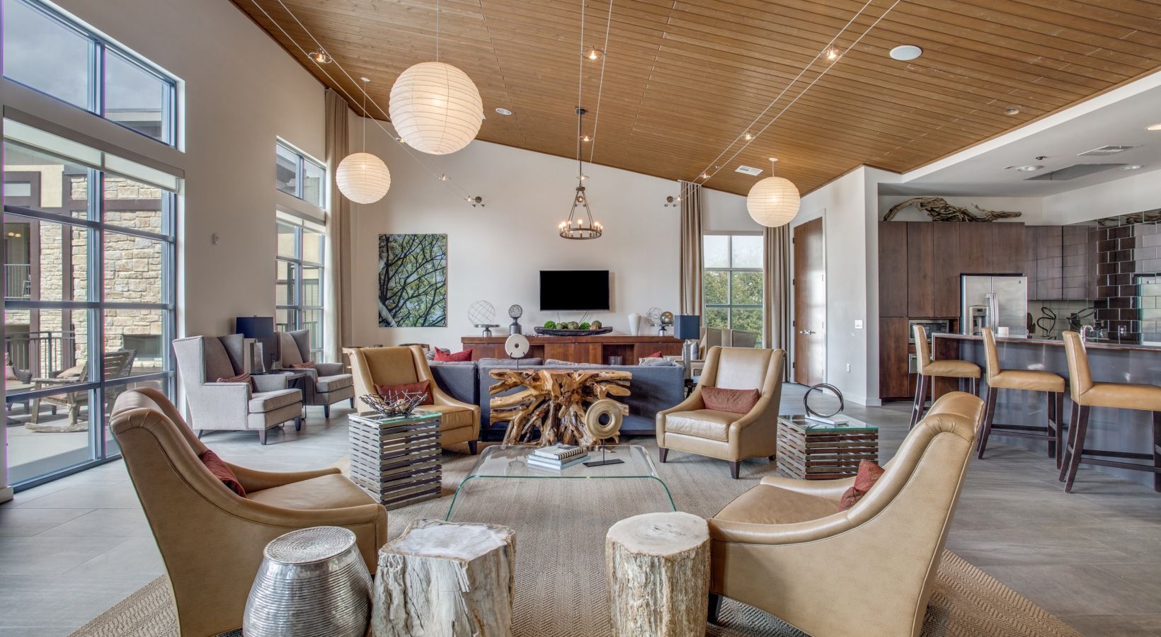 Modern lounge with round chairs, hanging globe lights, fireplace, and a bar area in a spacious lobby