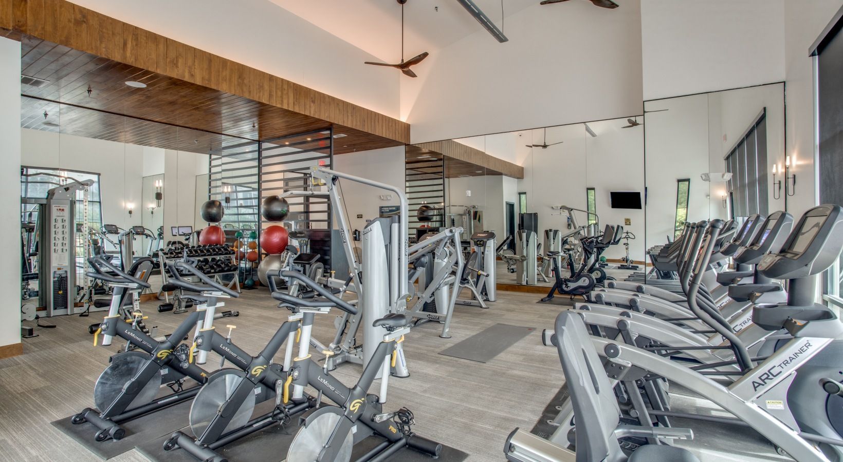 Modern gym with cardio machines, weight equipment, and mirrors in a bright room