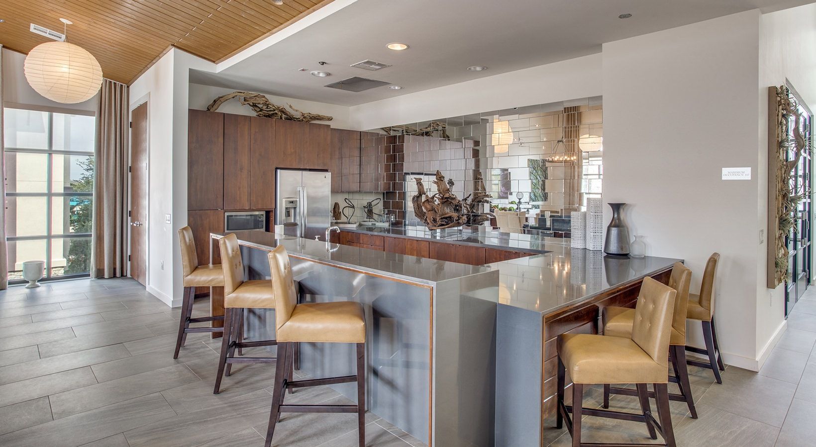 Modern kitchen and dining area with a large island, bar stools, wood cabinets, and stone accents