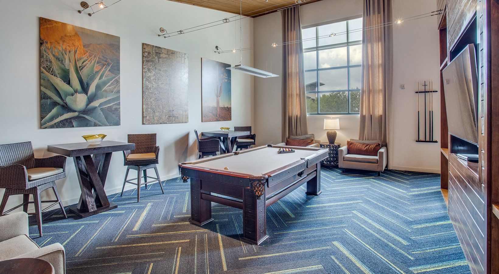 Stylish lounge with pool table, sofa seating, large window, and wall art in a modern room