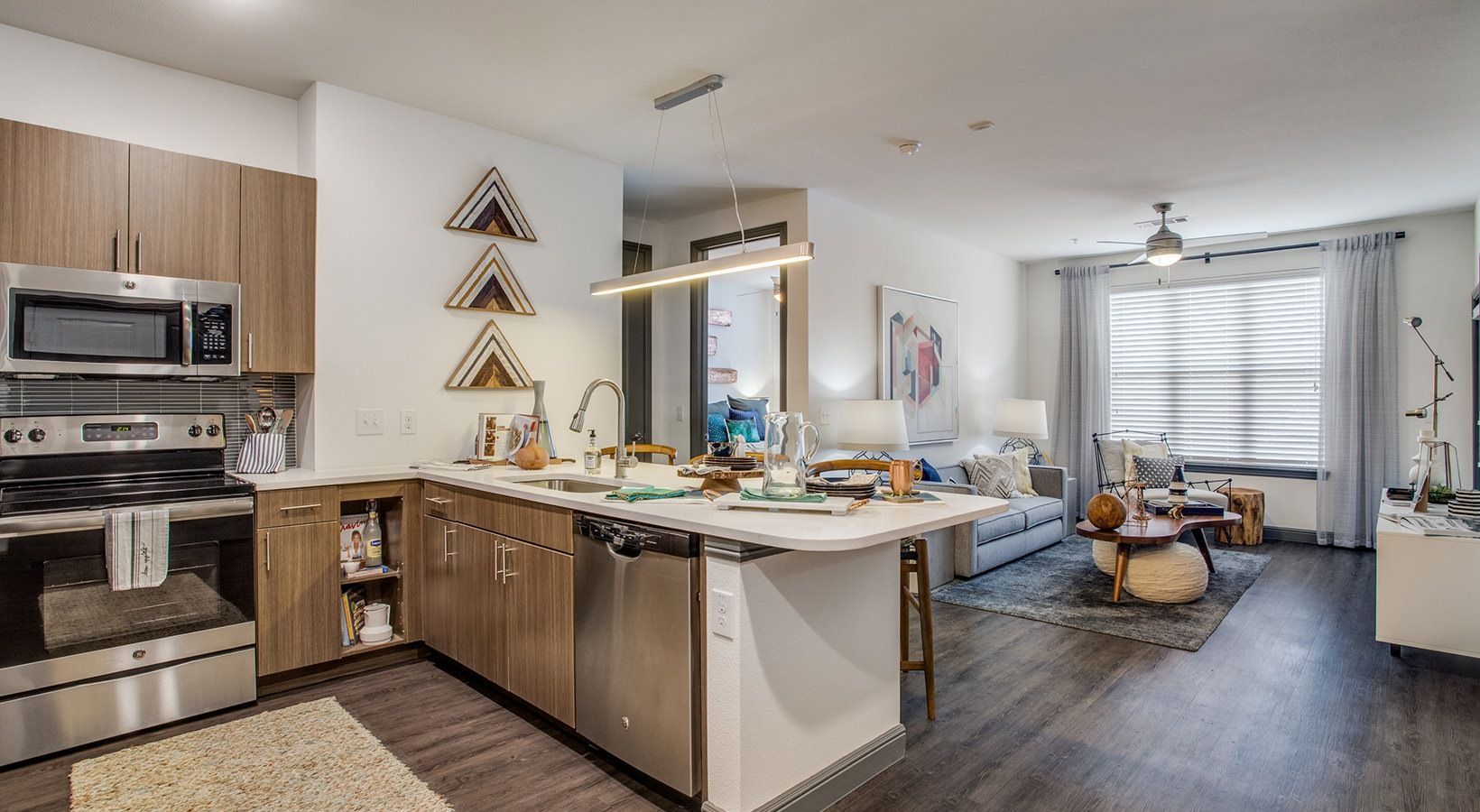 Open-concept kitchen and living room with stainless appliances, island, dining table, and large windows.
