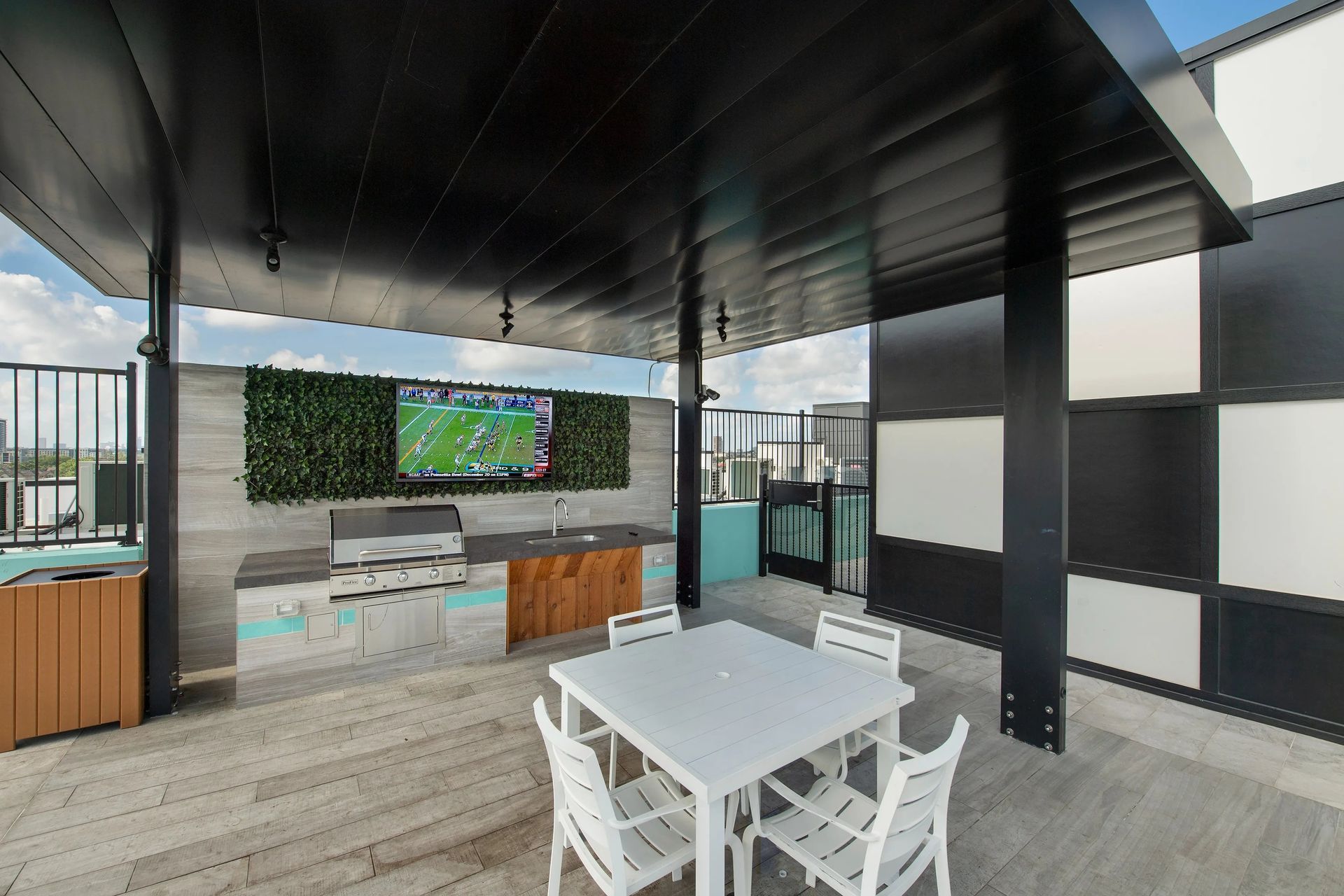 Outdoor patio with white table and chairs facing a TV under a covered pergola