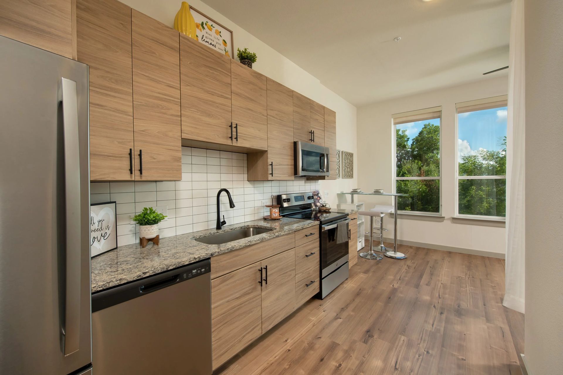 Modern kitchen with wood cabinets, black countertop, and dining area by a bright window