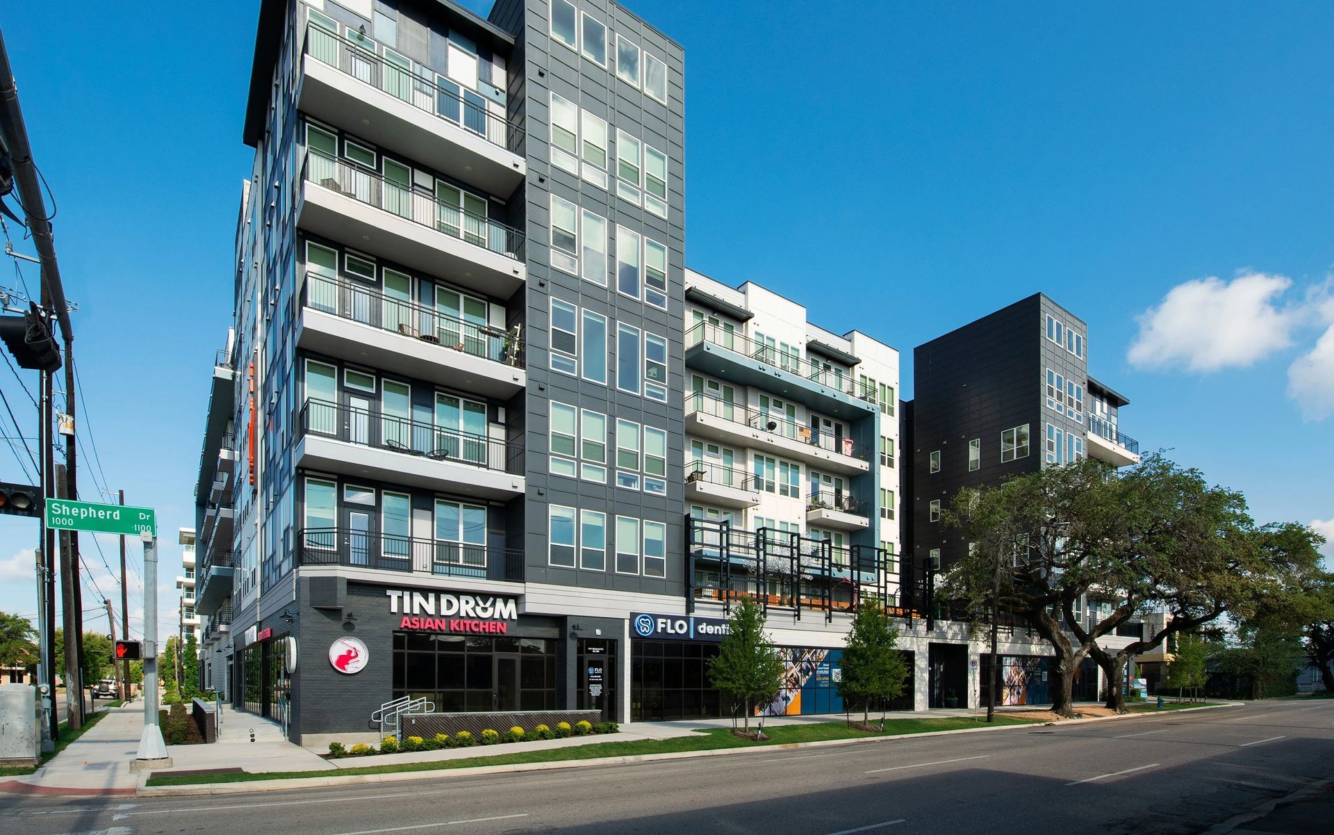 Modern apartment building with ground-floor shops on a sunny city street