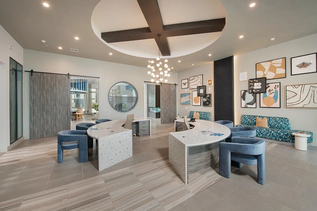 Modern office reception area with curved desks, teal chairs, and circular ceiling light fixtures