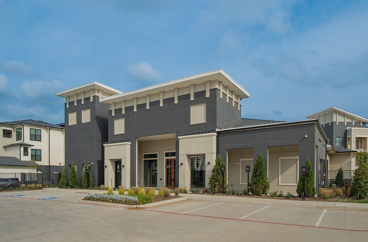 Modern two-story gray house with white trim and a spacious driveway under a blue sky